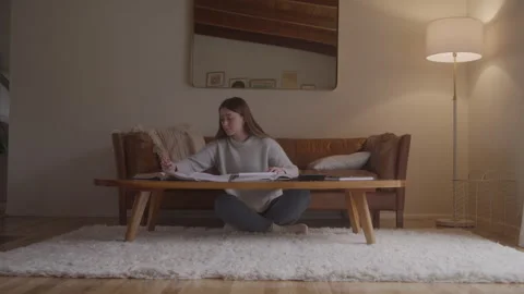 Woman Doing Homework On Coffee Table In Living Room Video stock 270330308