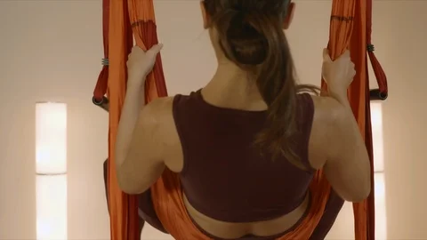 Woman doing inverted star pose at fly yoga class.Lady practicing yoga in hammock Stock Footage 127487451