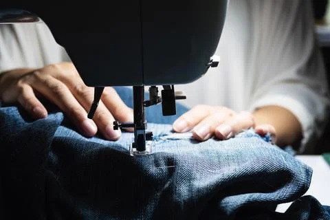 Woman doing jeans patchwork using sewing machine - home DIY sewing concept Stock Photos