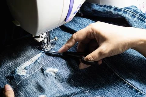 Woman doing jeans patchwork using sewing machine - home DIY sewing concept Stock Photos