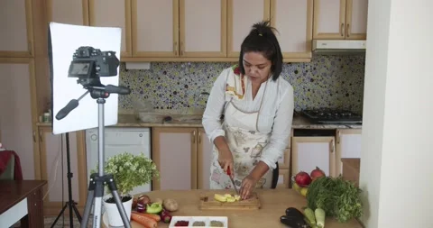 Woman doing live stream chops patato while cooking, wide shoot Video stock 142253571
