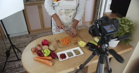 Woman doing live stream chops carrots while cooking, medium shoot Stock Footage 142253705