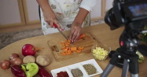 Woman doing live stream chops carrots while cooking, medium shoot 動画素材 142253753