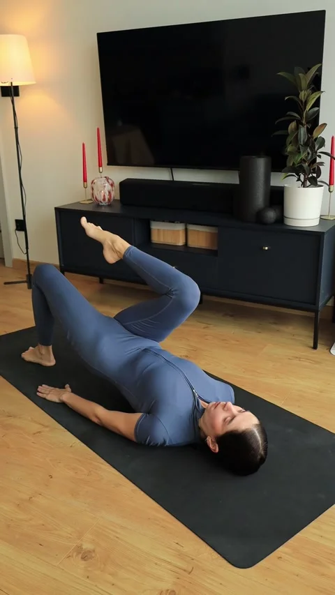 Woman doing lying single-leg lift and core activation exercise Stock Footage 322163872