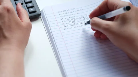 A woman doing math in a notebook using a calculator. Stock Footage 308957840