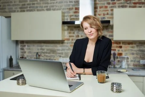 A woman doing notes during the report of a colleague at a video conference. Stock Photos