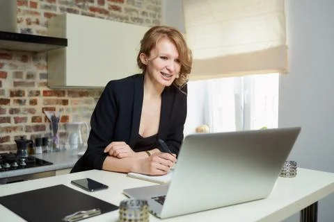 A woman doing notes during the report of a colleague at a video conference. Stock Photos