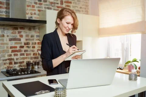A woman doing notes during the report of a colleague at a video conference. Stock Photos