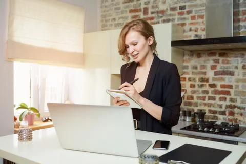 A woman doing notes during the report of a colleague at a video conference. Stock Photos