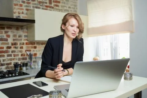 A woman doing notes during the report of a colleague at a video conference. Stock Photos