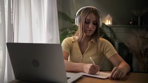 Woman doing online learning using note pad sitting at table in home interior Stock Footage 209827354