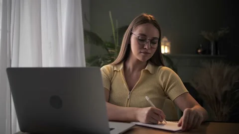 Woman doing online learning using note pad sitting at table in home interior Stock Footage 209828595