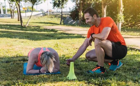 Woman doing planks with a personal trainer outdoors Stock Photos