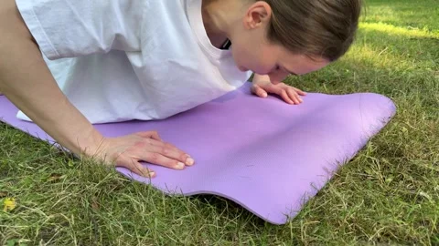 Woman doing push-ups on purple yoga mat on green grass outdoors 스톡 동영상 340515231