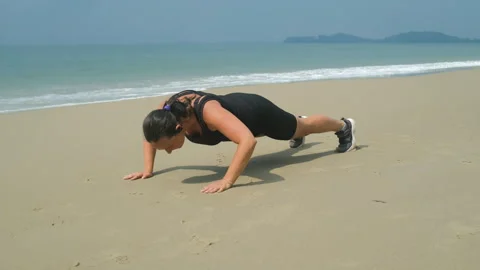 Woman doing push-ups on sandy beach shore Stockbeeldmateriaal 335255829