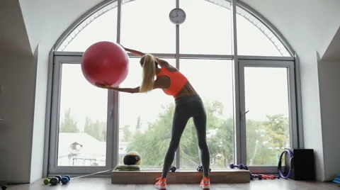 Woman doing a side stretching exercise using fitball in fitness studio Stock Footage