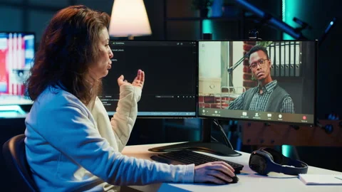 Woman doing software debugging helped by coworker in videocall Stock Footage 283596111