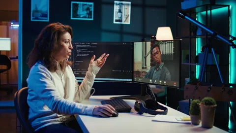 Woman doing software debugging helped by coworker in videocall Stock Footage 283692877