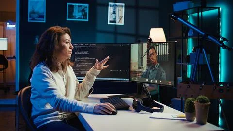 Woman doing software debugging helped by coworker in videocall 库存照片