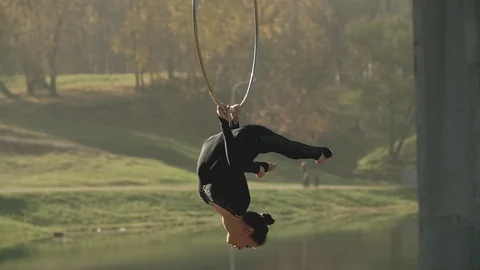 Woman doing some acrobatic elements on aerial hoop outdoors. Flexible girl Stock Footage 99220159