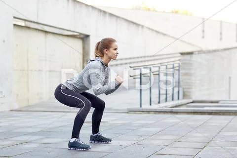 Woman doing squats and exercising outdoors Stock Photos