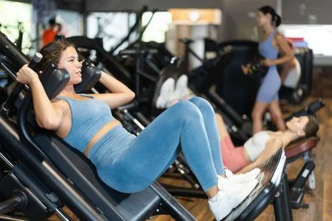Woman doing squats in a machine Stock Photos