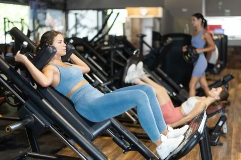 Woman doing squats in a machine Stock Photos