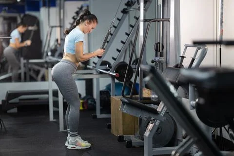 Woman doing triceps pushdown using cable machine in gym Foto stock