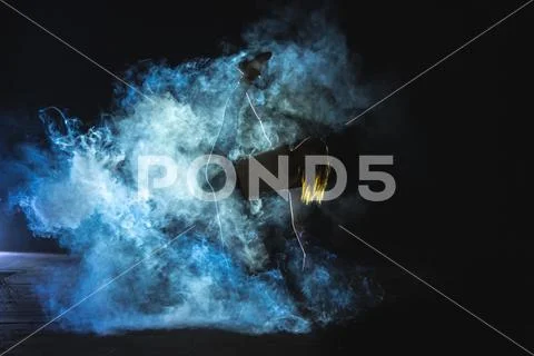 The woman doing vertical split in the smoke on the dark background Stock Photos