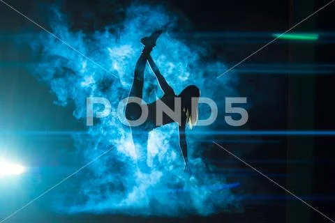 The woman doing vertical split in a smoke on the bright light background Stock Photos