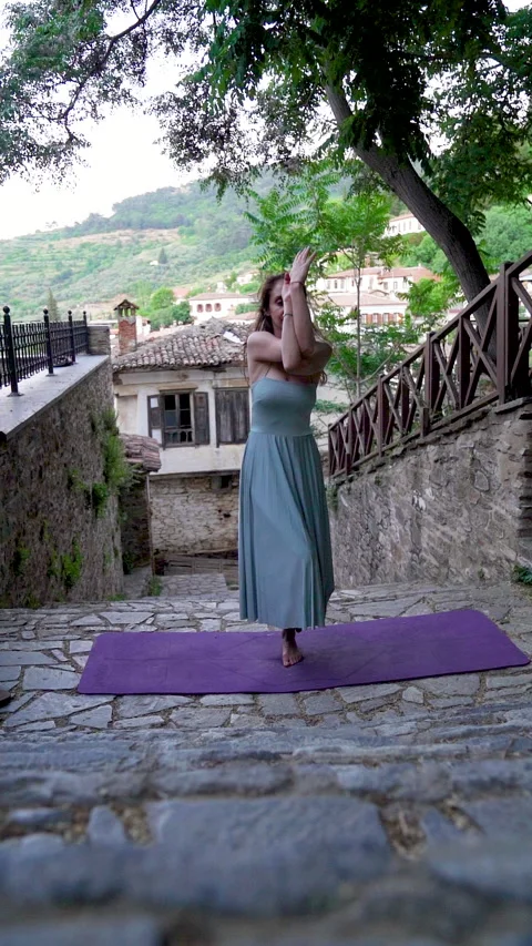 Woman doing yoga eagle pose on a historic street in Sirince village Stock Footage 336139672