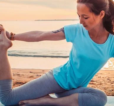 Woman doing yoga exercise on summer beach Stock Photos