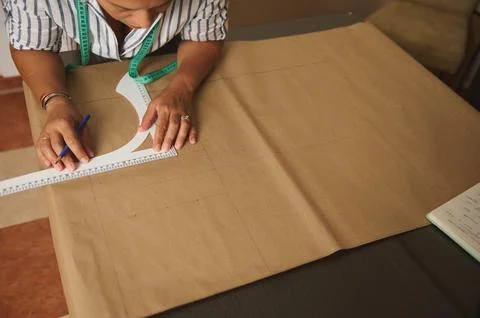 Woman drafting sewing pattern on kraft paper with measuring tape and ruler .. Stock Photos