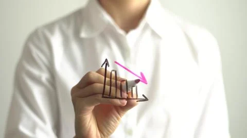 Woman drawing decrease diagram with red down arrow on transparent screen. Stock Photos