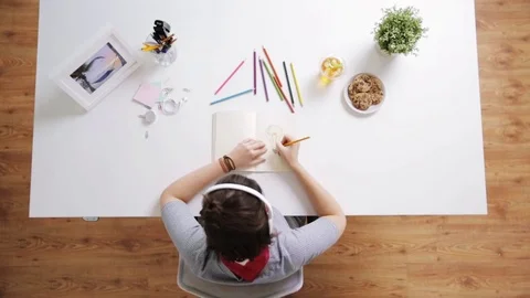 Woman drawing picture in notebook at home desk Stock Footage