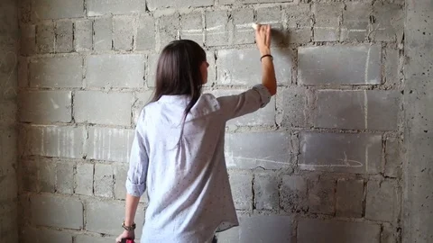 Woman drawing rectangle of future TV on wall of flat without finishing. Stock Footage 70628737