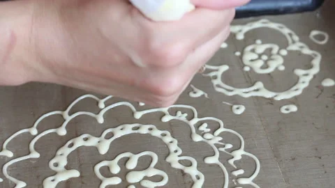A woman draws a dough pattern on a baking sheet. The process of making Swiss  Stock Footage 133061302