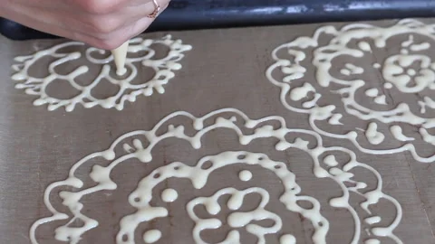 A woman draws a dough pattern on a baking sheet. The process of making Swiss  Stock Footage 133064198