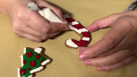Woman draws pattern on gingerbread in shape of candy cane and Christmas tree Stock Footage 287519745