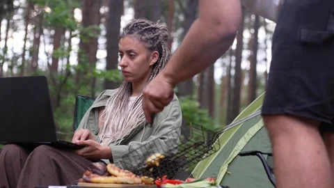 Woman with dreadlocks working on laptop while camping Stock Footage 327607256
