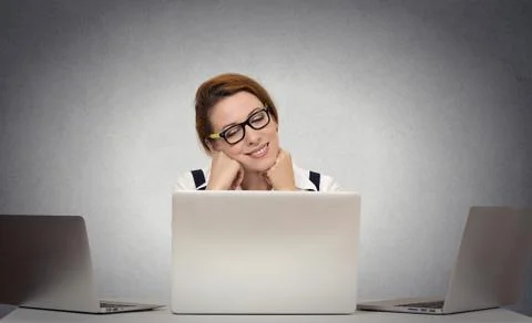 Woman dreaming while working on multiple computers Foto stock