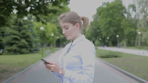 Woman in dress code standing in park and make a call Stock Footage 92528764