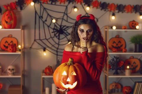 Woman dressed up as devil doing Shh finger on lip gesture at secret Halloween Stockfoto's