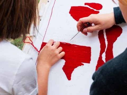 Woman dressed in medieval clothes is teaching girl embroidery. Annual festiva Stock Photos