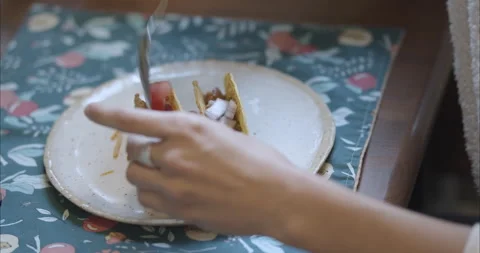 Woman dressing hard shell corn tacos and filling with vegetables and toppings Stock Footage 155547972