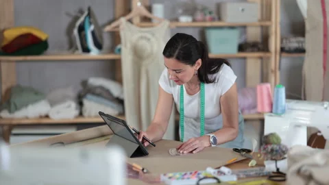 Woman dressmaker makes pattern using tablet Stock Footage 310951043