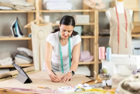 Woman dressmaker makes pattern using drawing on tablet Stock Photos