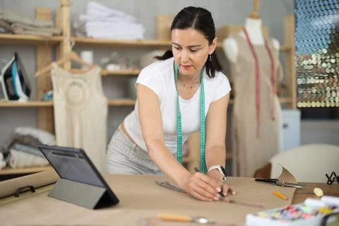 Woman dressmaker makes pattern using drawing on tablet Stock Photos
