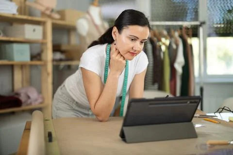 Woman dressmaker makes pattern using drawing on tablet Stock Photos