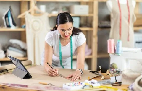 Woman dressmaker makes pattern using drawing on tablet Stock Photos